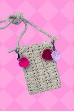 a crocheted bag with two hearts attached to it on a pink and white checkered background