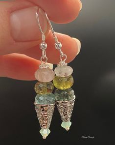 Indulge in the mesmerizing beauty of these Multicolor Gemstone Dangle Drop Earrings. Perfect for someone who loves to make a statement with their accessories, these earrings feature a mix of natural quartz, heated aquamarine, aventurine, and Swarovski crystals in shades of green and blue. The silver plated components add a touch of elegance to the tribal/boho style design. The total length of these earrings is 4cm, making them a great addition to any outfit. These earrings are not only eye-catching but also versatile, making them a perfect gift for her. Let her embrace her unique sense of style with these beautiful and natural gemstone earrings. Please note that the dimensions, colors, and patterns of natural gemstones may vary slightly, making each pair of these earrings one-of-a-kind. Ad Bohemian Earrings With Gemstone Accents For Gift, Bohemian Green Earrings With Gemstone Accents, Bohemian Green Jewelry With Gemstone Accents, Bohemian Teardrop Earrings With Gemstone Accents, Fusion Style Dangle Jewelry For Jewelry Making, Elegant Dangle Crystal Earrings For Healing, Silver Dangle Earrings With Stones, Fusion Style Dangle Jewelry With Gemstone Accents, Fusion Dangle Earrings With Gemstone Accents