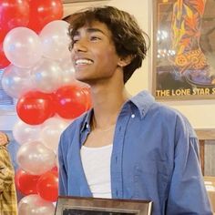 a young man standing next to balloons and a plaque