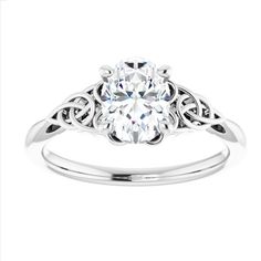 a white gold engagement ring with an oval cut diamond in the center and filigrees around the band