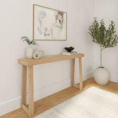 a wooden table sitting on top of a hard wood floor next to a white vase