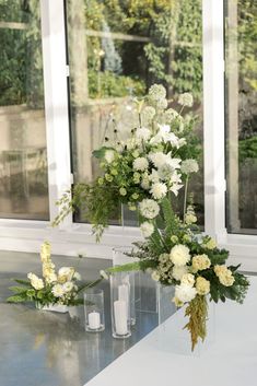 two vases filled with white flowers on top of a table