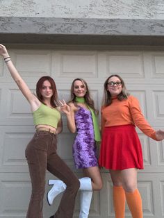 three young women posing in front of a garage door with their arms up and legs crossed