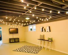 an empty room with lights strung from the ceiling, and a rug on the floor