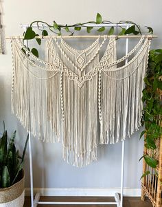 a macrame hanging on a rack next to a potted plant