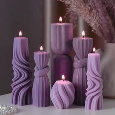 purple candles are sitting on a table next to pearls and a vase with some flowers in it