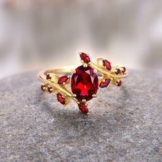 a red ring sitting on top of a stone covered surface with gold accents and garnets