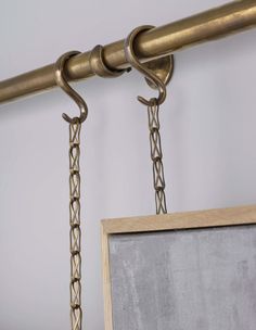 a chalkboard hanging from the side of a metal rod with two hooks on it