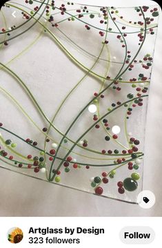 a glass plate with beads on it and green stems sticking out of the top, sitting on a white surface