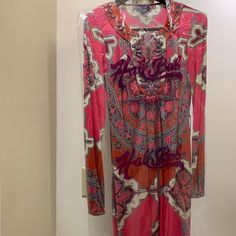 a pink and red dress hanging up on a rack in front of a white wall