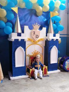 a little boy sitting on top of a chair in front of a blue and white castle