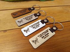 three wooden keychains with engraved words on them sitting on a table next to a plant