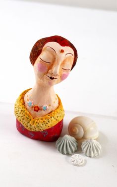 a ceramic figurine is sitting next to two seashells