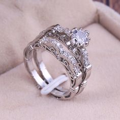 two wedding rings sitting on top of each other in a ring box with white stones