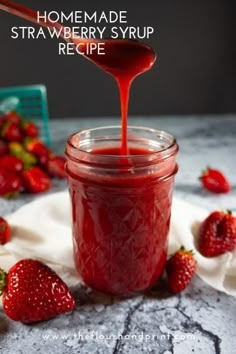 a spoon full of strawberry jam being poured into a jar