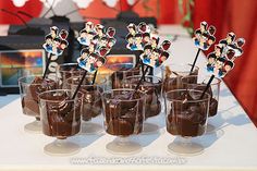 chocolate cups with mickey mouse toppers and candy sticks in them on a white table