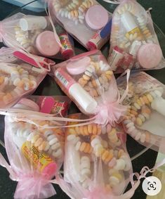 several small bags filled with candy and other candies on a glass plate, some wrapped in pink ribbon