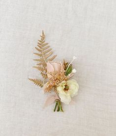 a bouquet of flowers is laying on a white surface with ferns and other things in the background