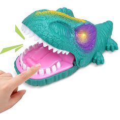 a hand pointing at a toy alligator with its mouth open