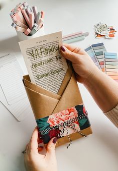 a person is holding an envelope with a card in it and some papers on the table