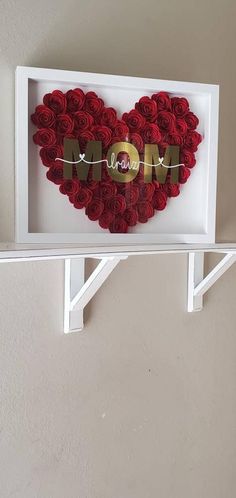 a heart made out of red roses with the word mom spelled in gold on it