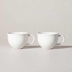 two white cups sitting side by side on a table