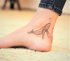 a woman's foot with a whale tattoo on it