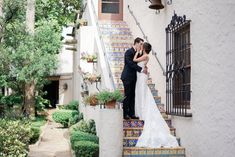 a bride and groom kissing on the steps of an old spanish style house in san francisco