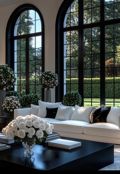 a living room filled with white furniture and large windows overlooking a lush green park behind it