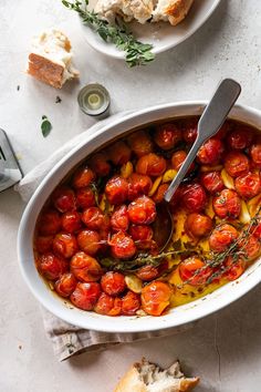 a white bowl filled with tomatoes and bread on top of a table next to a fork