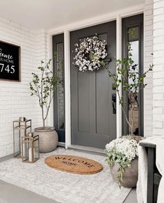 a front door with two planters and a welcome mat on the floor next to it