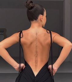 the back of a woman's body with her hands on her hips, wearing a black dress