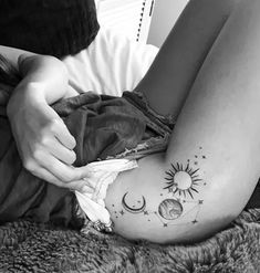 a woman is laying on her stomach with tattoos on her legs and the sun and moon