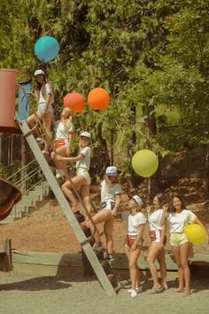 a group of young women standing on top of a wooden slide next to each other