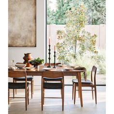 a dining room table with chairs and plates on it in front of a large window