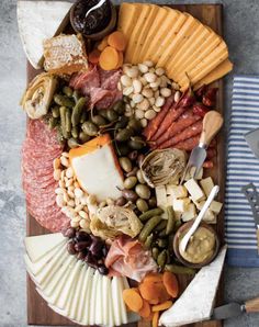 a wooden platter filled with meat, cheese and veggies