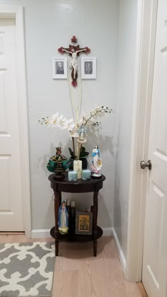 a cross is on the wall above a table with candles and other items in front of it