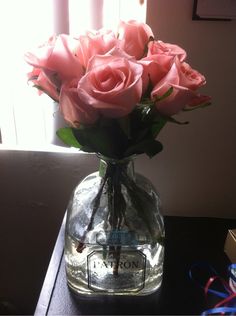 a vase filled with pink roses sitting on top of a table next to a window