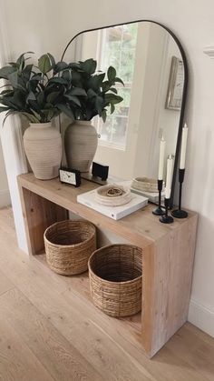 a wooden shelf with two baskets on it and a large mirror in the corner behind it