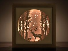 a paper cut deer and her fawn in the woods at night with lights on