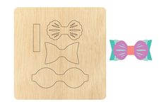 a wooden cutting board with a bow tie and two pieces of paper cut out on it