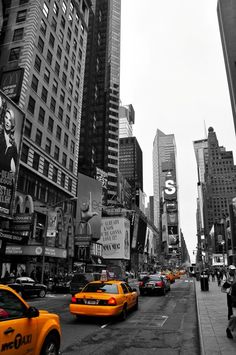 taxis are driving down the street in new york city, ny on a cloudy day