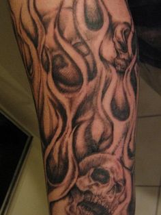 a man's leg with tattoos on it that has skulls and flames coming out of them