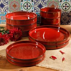 red dishes are sitting on a table with flowers