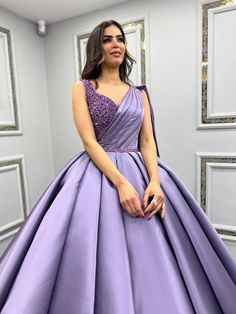 a woman in a purple ball gown posing for the camera with her hands on her hips