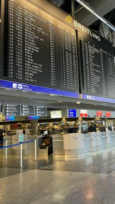 an airport terminal with many electronic signs on the wall