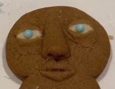 a close up of a cookie shaped like a person's face with blue eyes