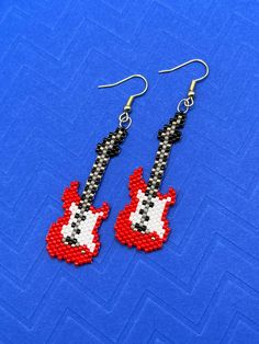 a pair of red and black beaded guitar earrings on a blue background with the words rock n roll written across it