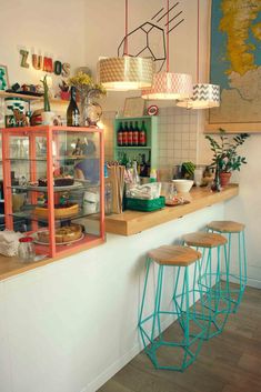 a counter with three stools in front of it and shelves full of food on the wall