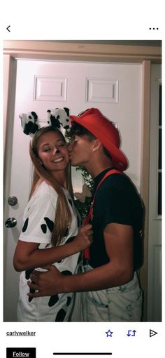 two people standing next to each other in front of a door and one is kissing the other